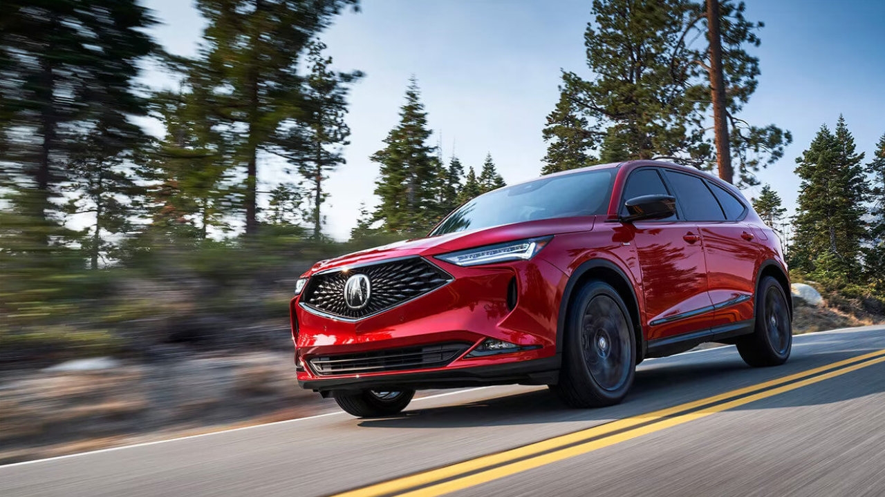 vue latérale avant d'une Acura MDX 2024 sur une route en forêt
